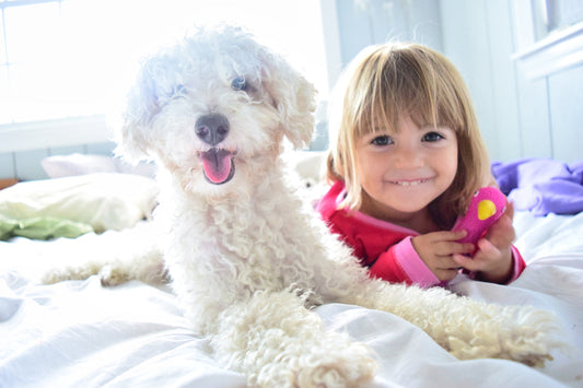 little girl laying with a poodle dog